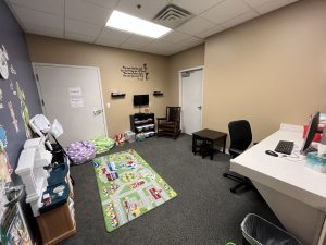 Photo of study room with computer and office chair, toys and seating for children, TV and DVD player